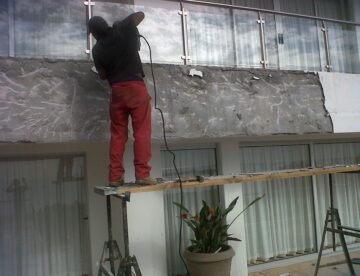 Builder repairing damp proofing on a balcony wall to prevent moisture and mould damage
